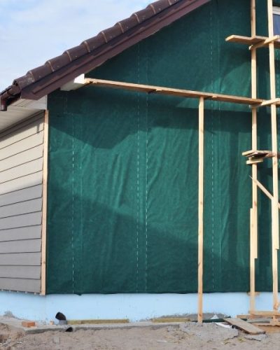 Building house with wall insulation, waterpfoof membrane, plastic siding, guttering and foundation insulation with styrofoam